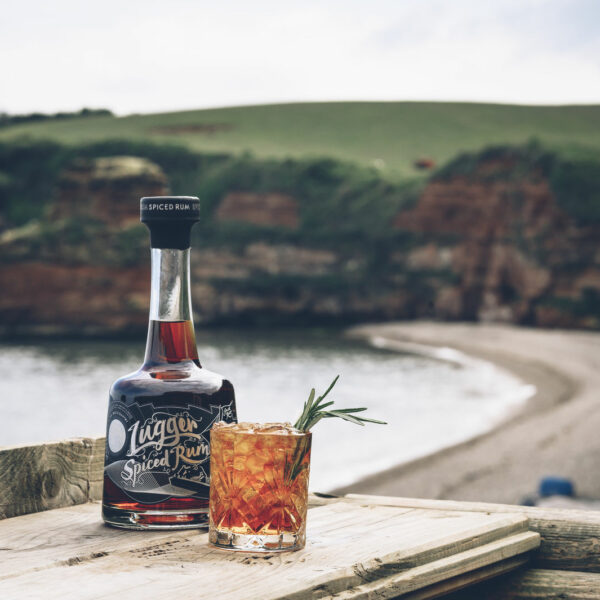 lyme bay lugger rum bottle with glass by the seafront