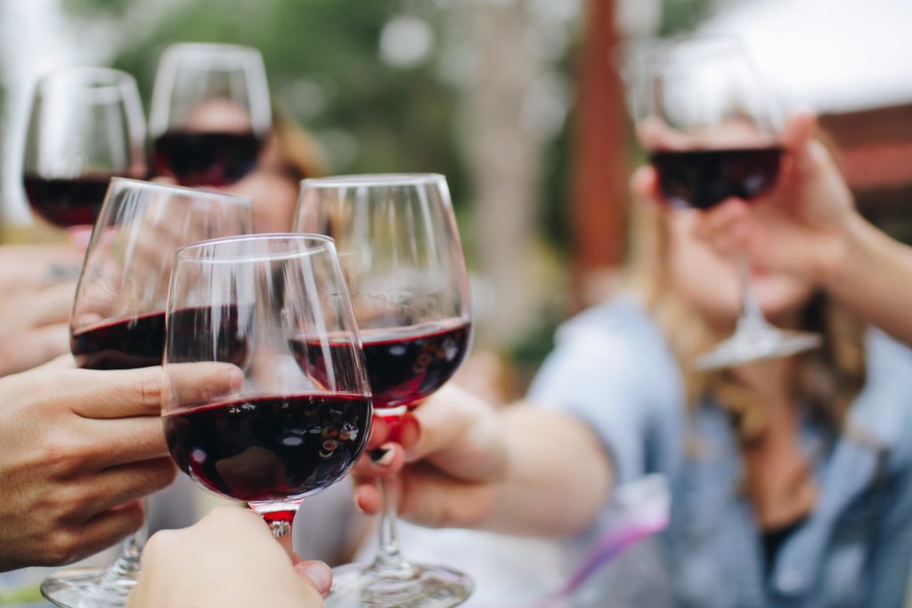 people toasting with red wine glasses