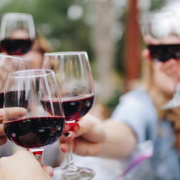 people toasting with red wine glasses