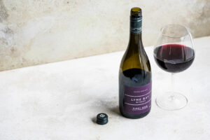 lyme bay winery pinot noir 2020 bottle with glass on a concrete surface