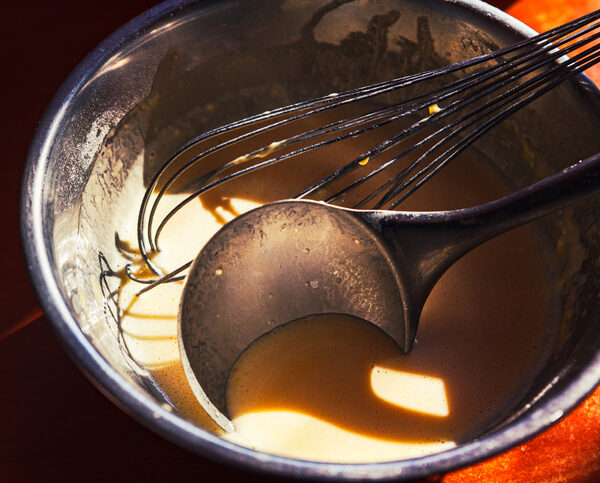 Pancake batter in a bowl with a ladle and whisk